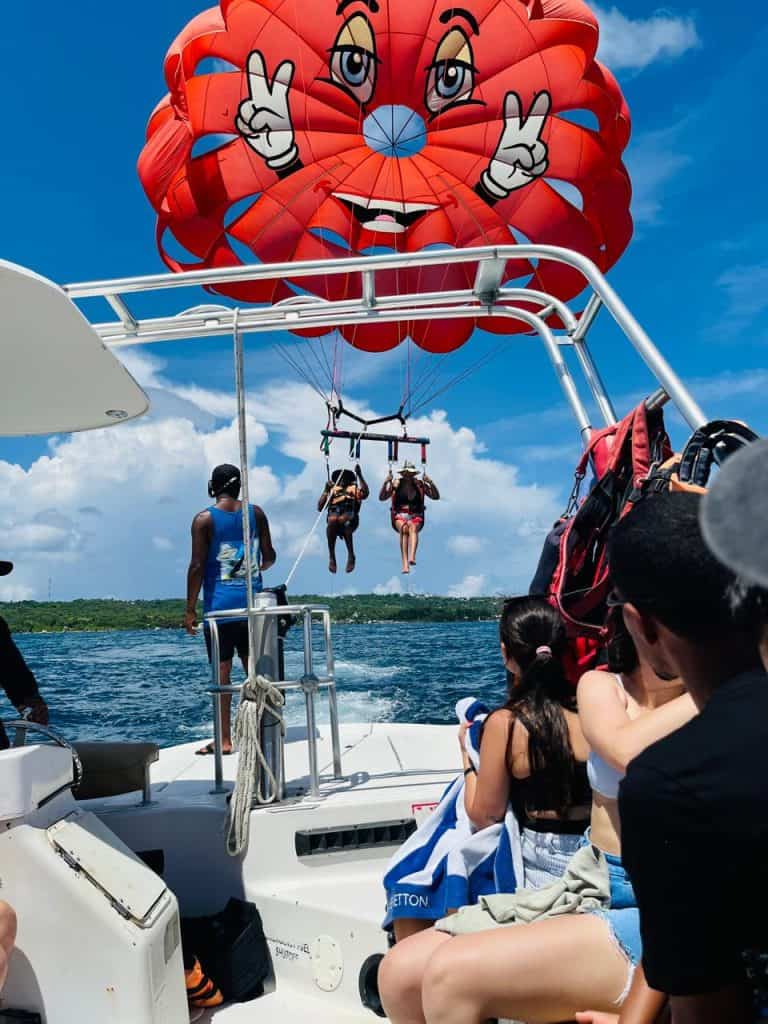 Colorful hot air balloon with smiling face, kids parasailing above water, adventure, travel, and outdoor fun.