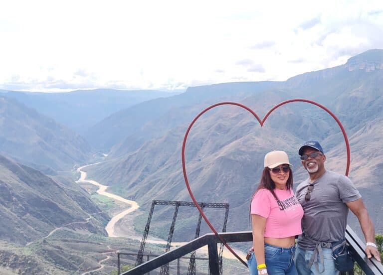 Couple enjoying scenic mountain view at Heart-Shaped Frame in lush landscape.