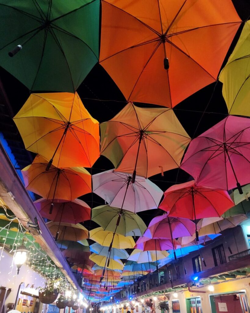 Vibrant umbrellas decoratively suspended above a bustling street in Guatapé, Colombia.