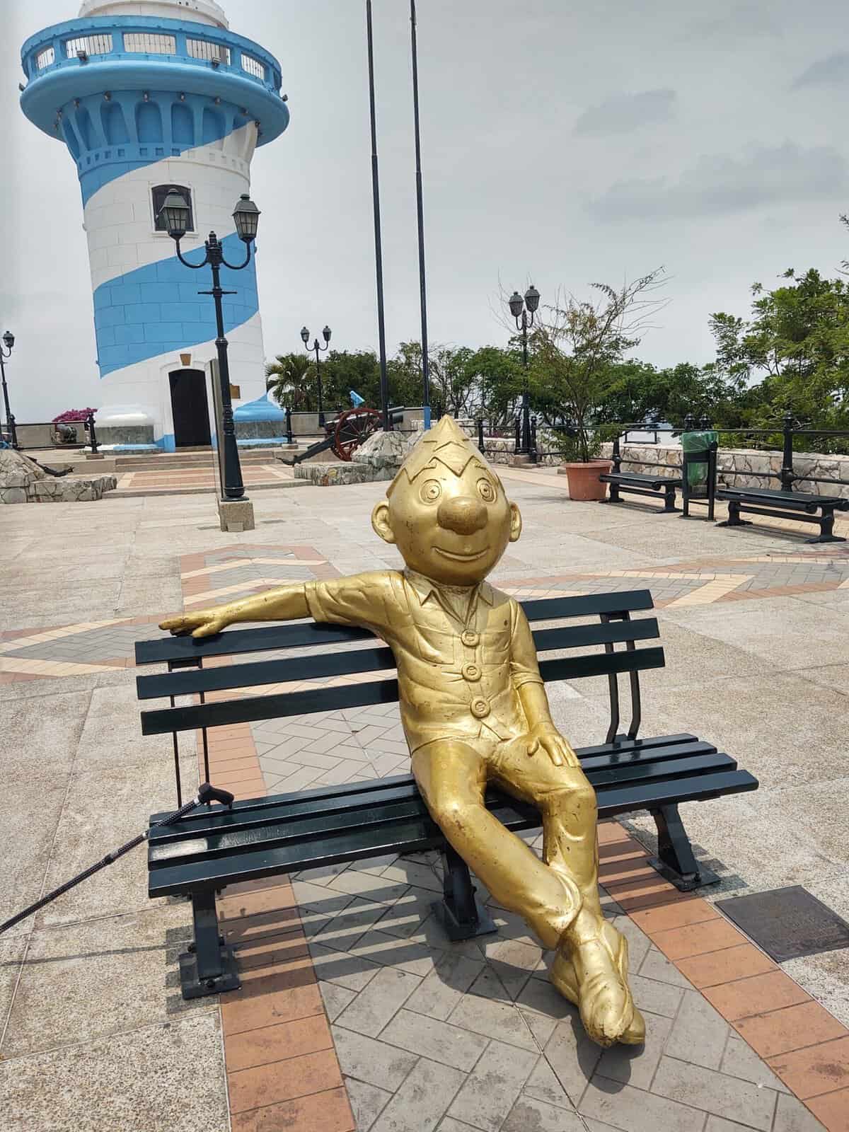 Colorful lighthouse with a whimsical golden sculpture sitting on a bench.